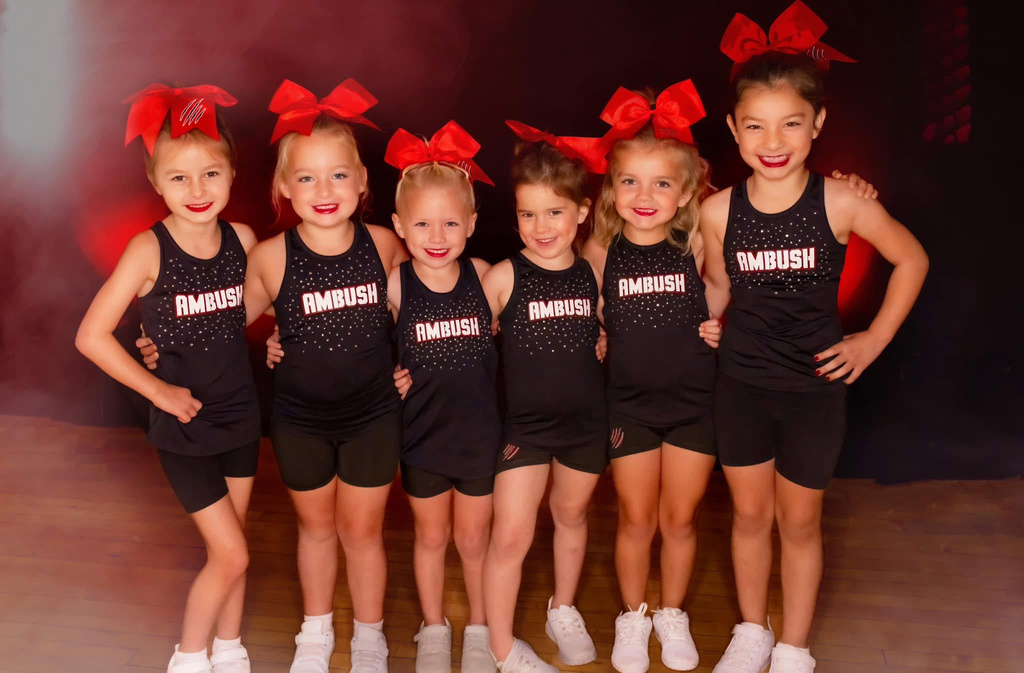 Young Ambush cheerleaders posing with red bows in black tank tops